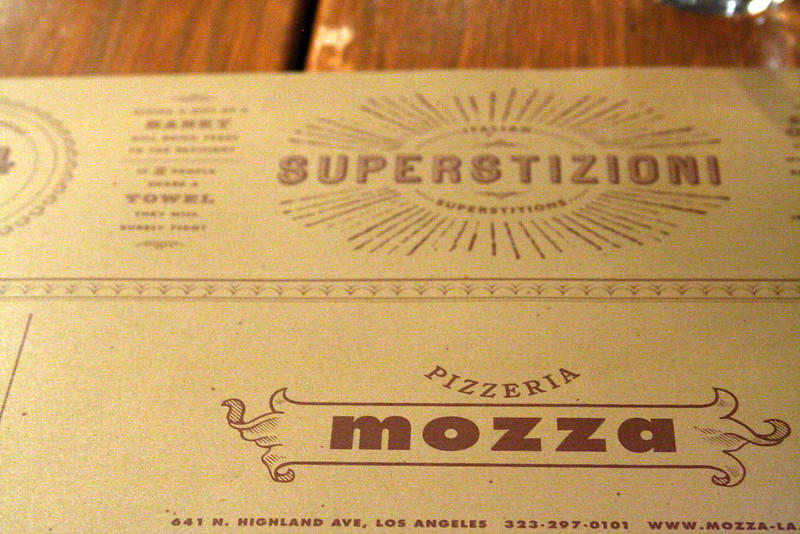 The place setting at a previously Mario Batali-owned restaurant called Pizzeria Mozza. Their current menu has antipasti (which are appetizers), insalate (which is a salad), Pizza, and Dolci (which is dessert)
