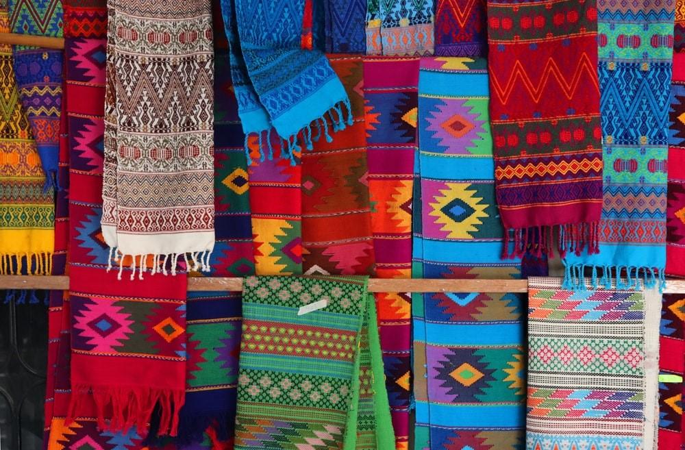 A lot of multicolored scarfs with traditional Aztec and Pre-Colombian textile motifs. Latin American fashion borrows heavily from the indigenous motifs and textile work of Pre-Colombian cultures. Mexican pop culture often uses these colors and symbols to exhibit traditional authenticity