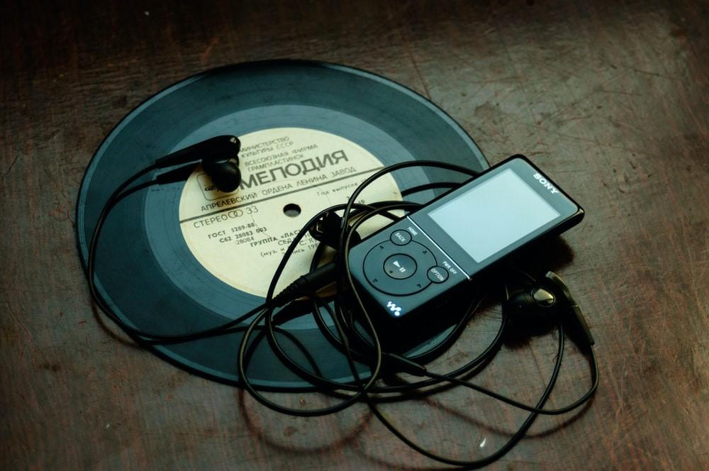 A Sony Walkman is lying on a wooden table with a black music record in the background. Thanks to comprehensive technological advances, it is now much easier for singers to train using different voice training software