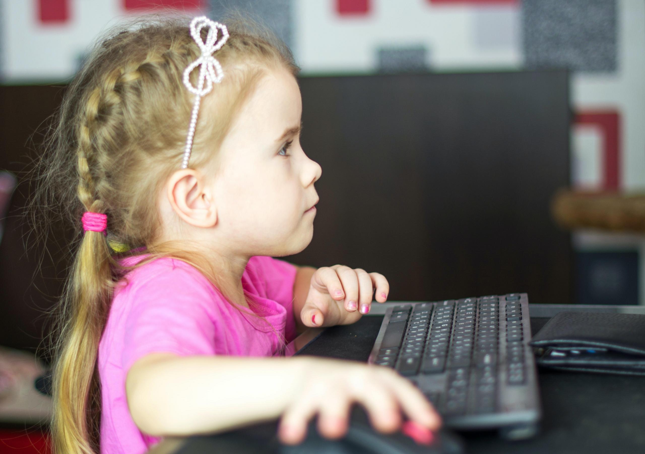 A little kindergarten girl solves a math puzzle on her computer. The best math apps gamify their maths lessons to make them more exciting and fun
