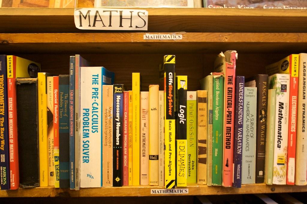 Multiple books on calculus, algebra, and mathematics lined up on a library shelf