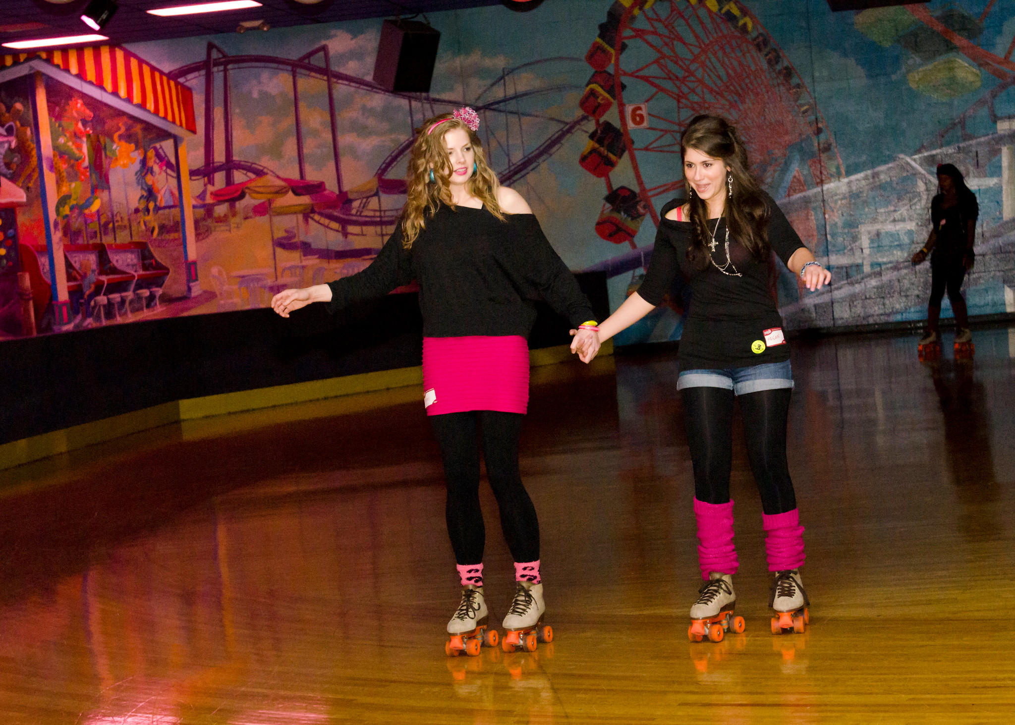 Two girls dressed in 80s clothing roller skating