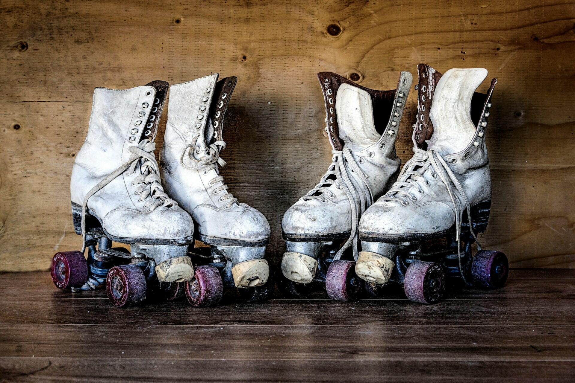 Four worn white roller skates standing on a wooden shelf
