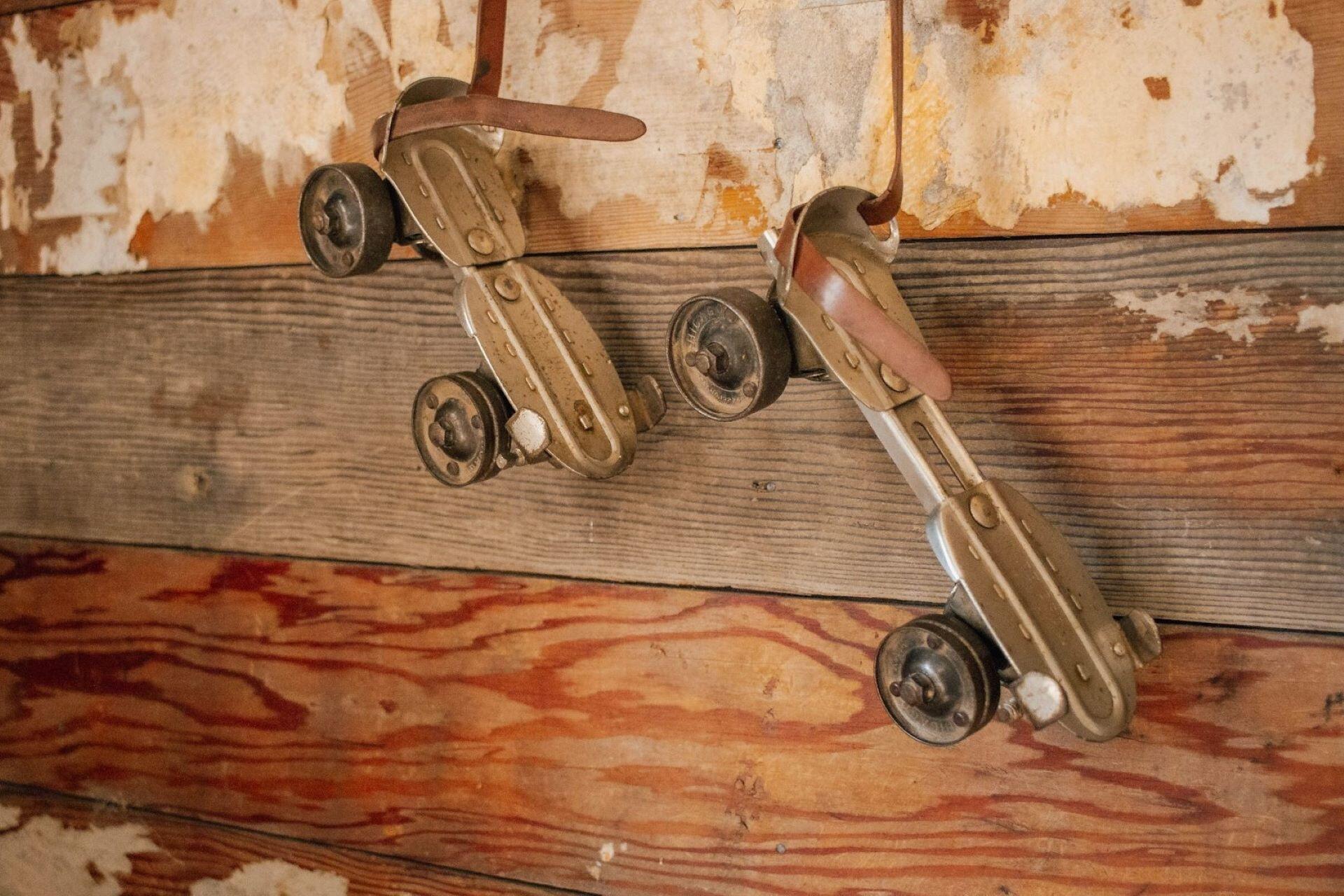 Pair of vintage metal roller skates mounted on a wooden wall