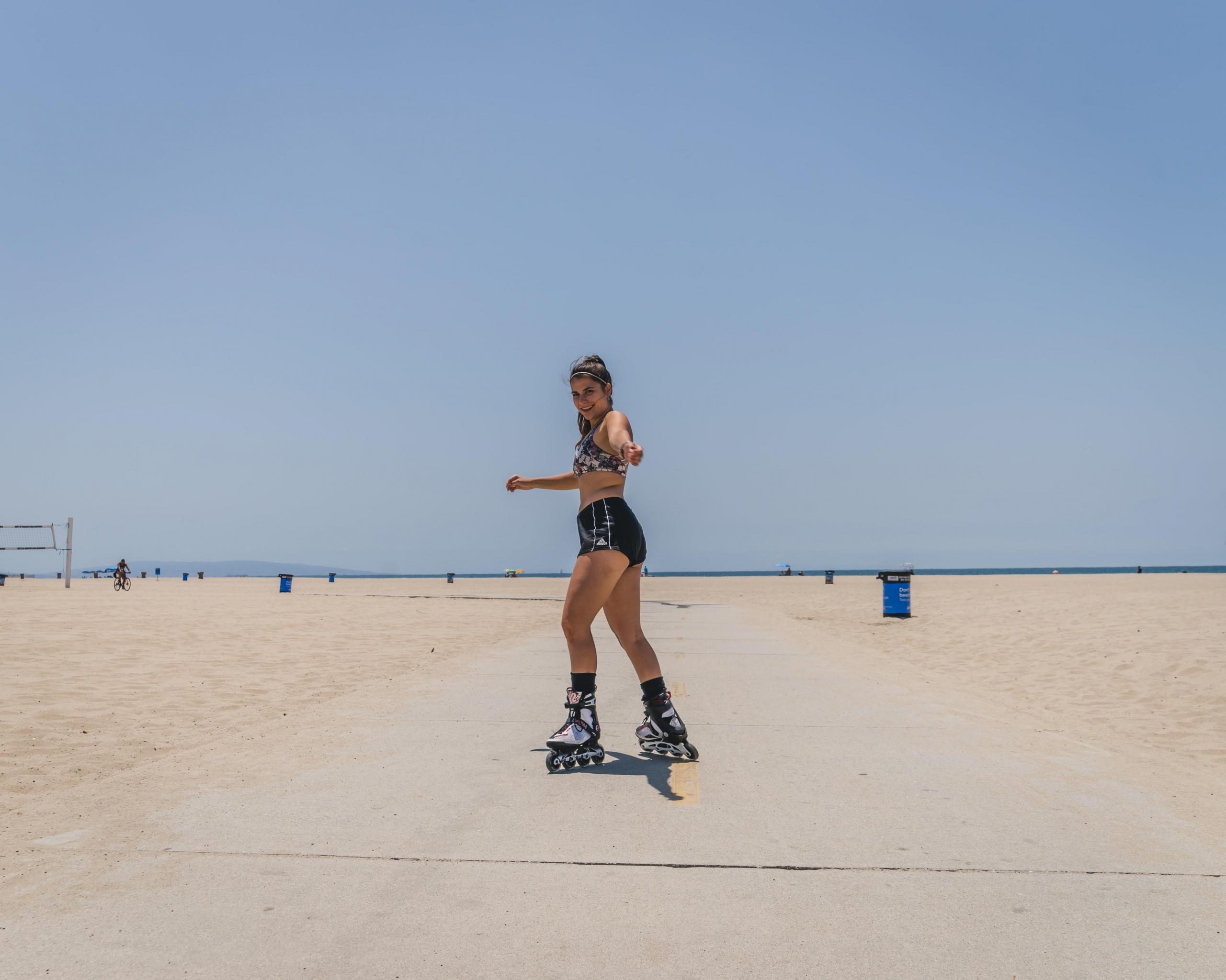 A skater roller skates on white sand near the Ohio beach