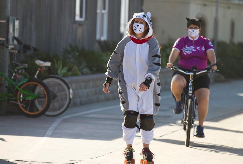 Two people with whisker masks skating and cycling together