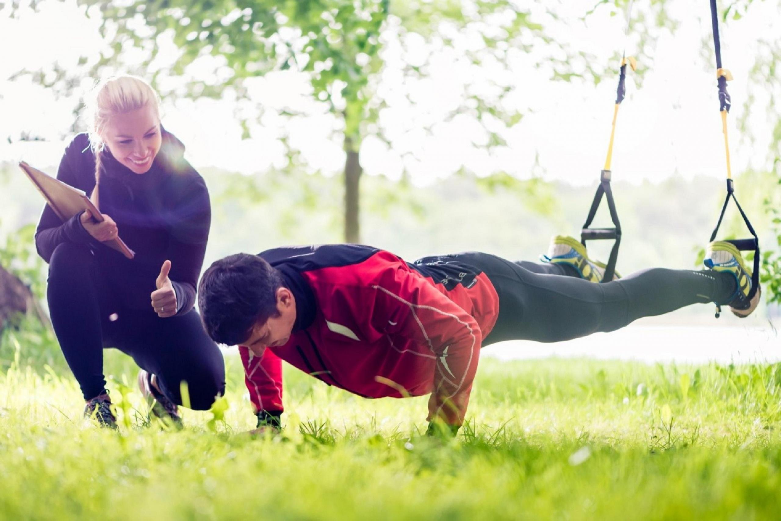 A gym trainer encouraging their client while they exercise