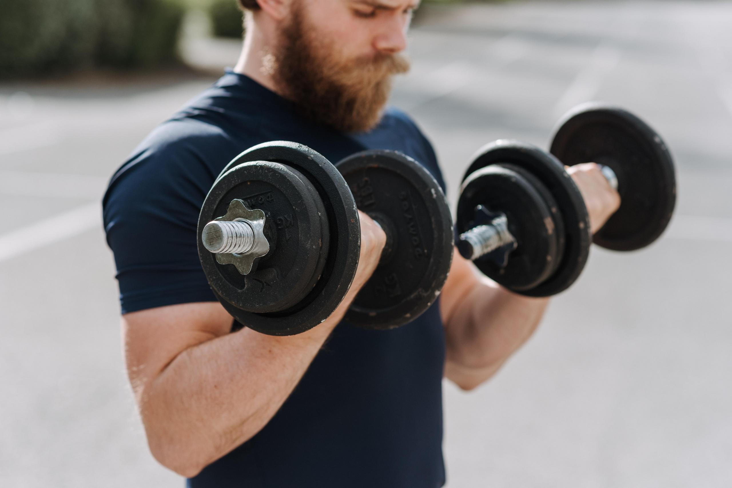 Man lifting two dumbbells in the street
