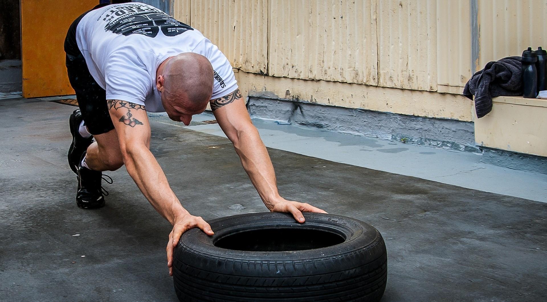 A gym-goer trains by pushing a tire