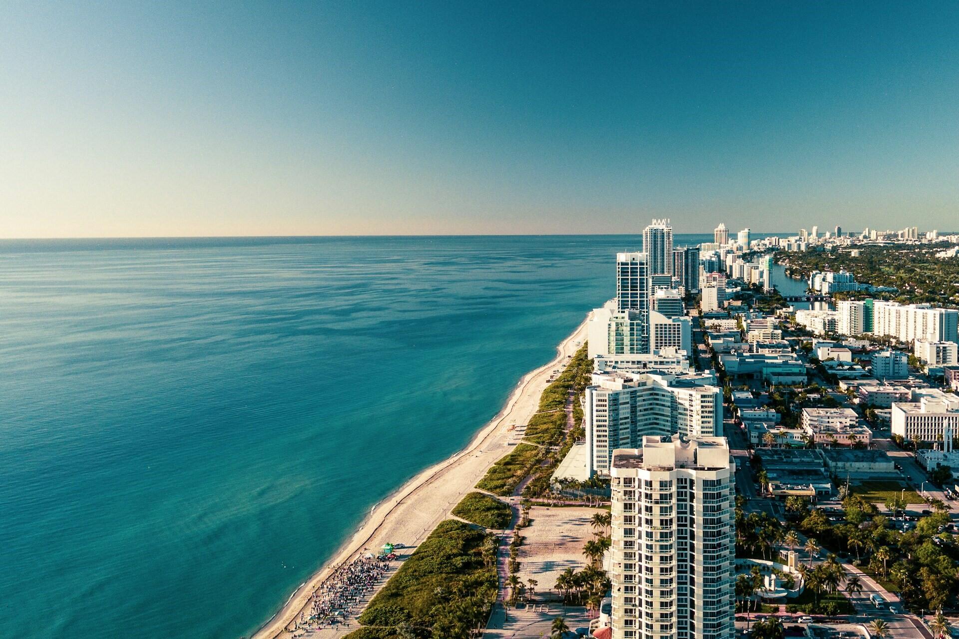 Aerial view of a turquoise coastline with high-rise buildings and a long beach.