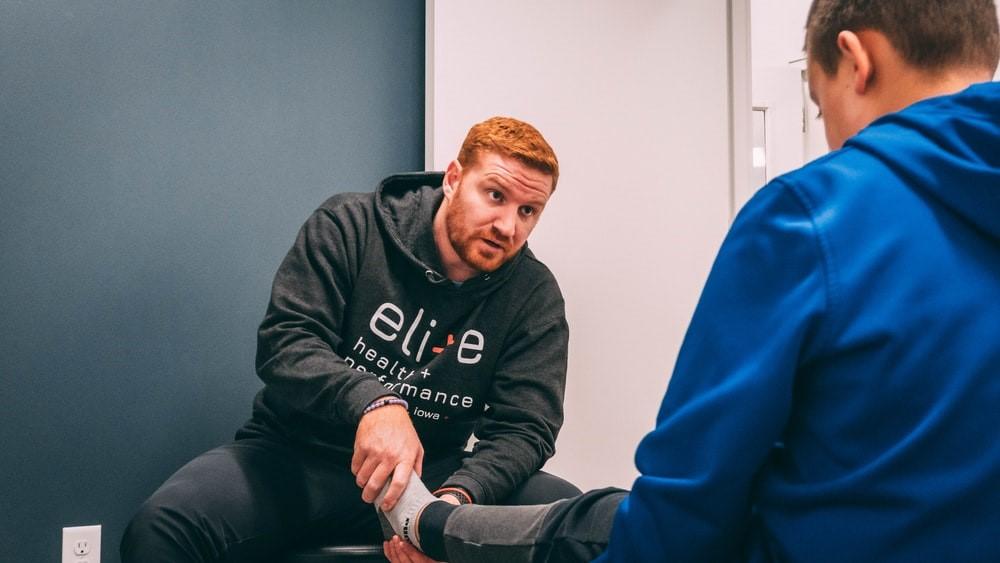 A trainer prodding and diagnosing their client's discomfort