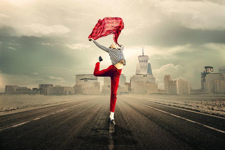 A girl holding a scarf and dancing with the city skyline behind her