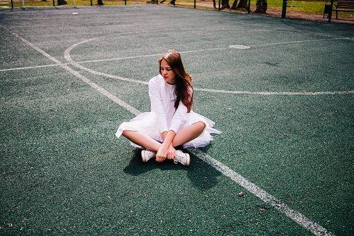 A woman sitting on an empty tennis court