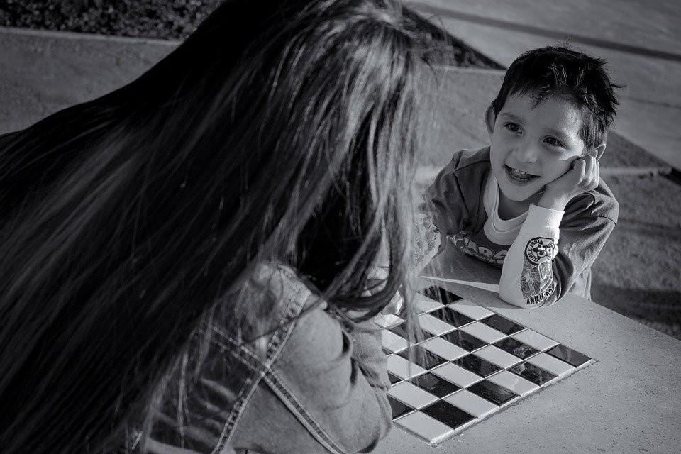 A mother teaching her son how to play chess