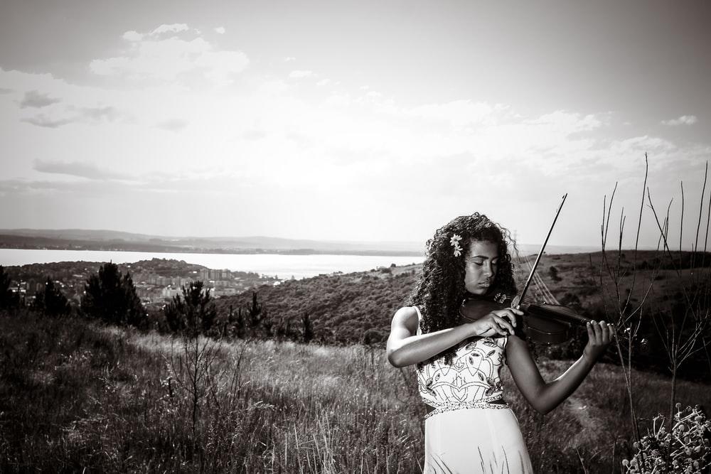 A girl in a white dress, playing the violin in the fields