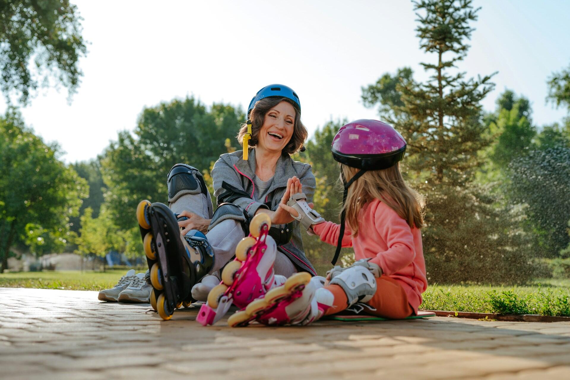 A grandma and her granddaughter high fiving with roller blades on.