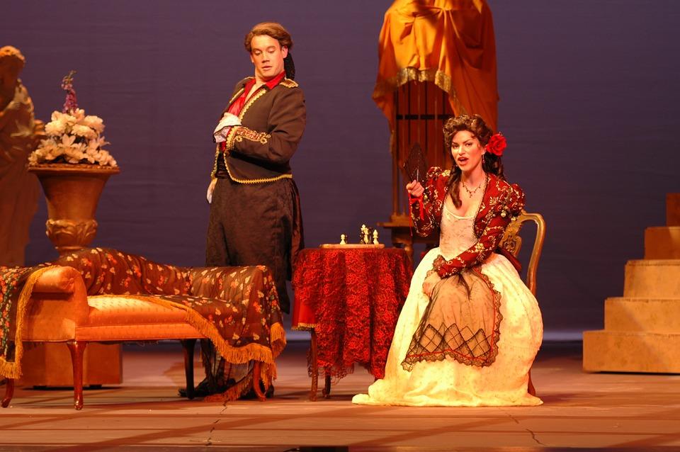 A man and a woman dressed in traditional theatre costumes