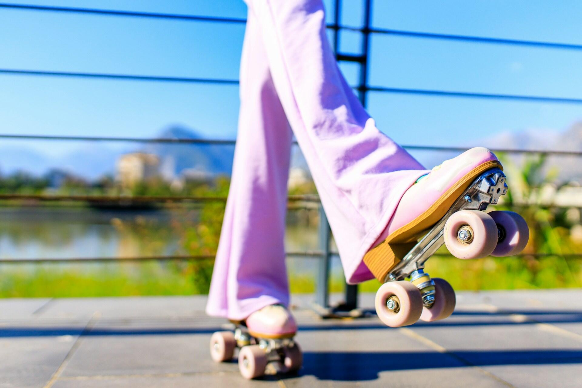 Someone in purple pants skating with one foot off the ground.