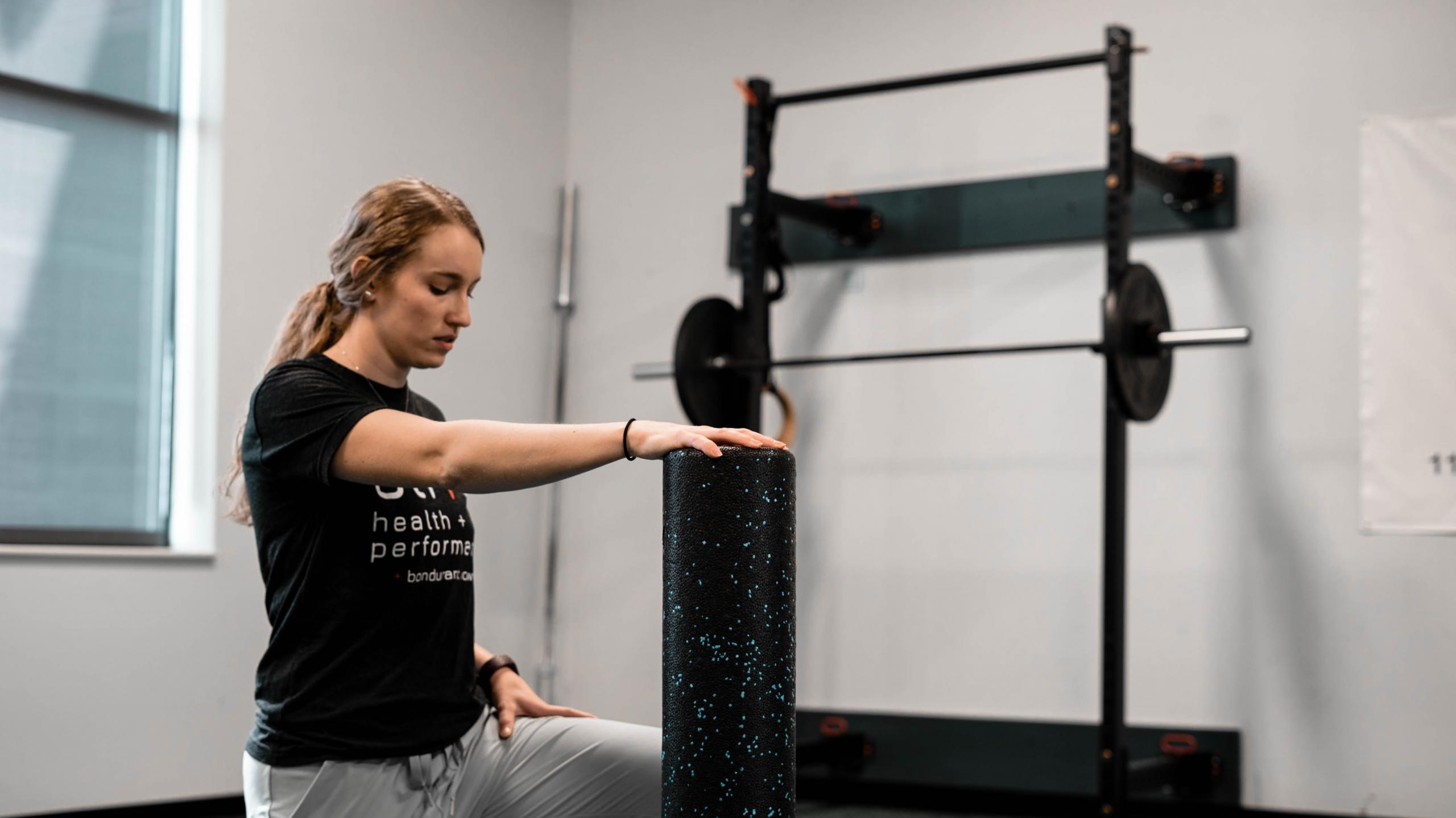 A trainer in black crew-neck t-shirt and gray pants working out at a gym