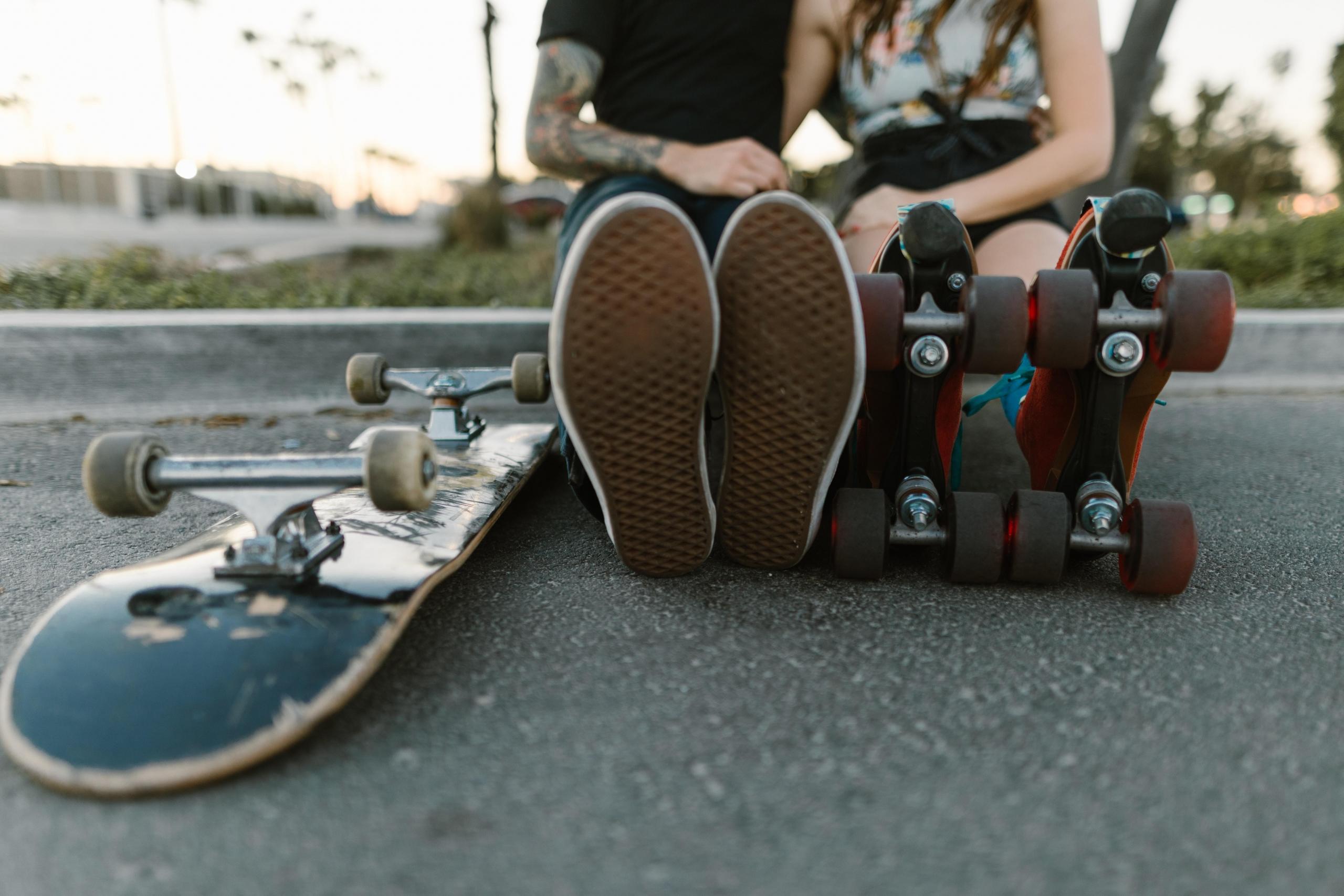Two people sitting on the ground with roller skates
