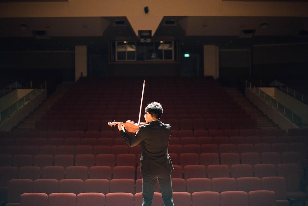 A musician playing violin in an empty theatre