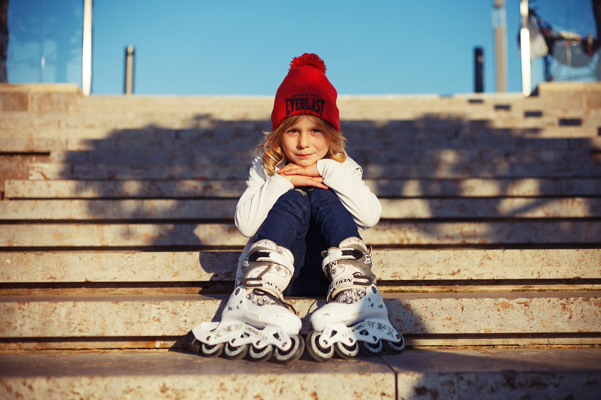 A girl wearing her rollerblades and sitting on stairs