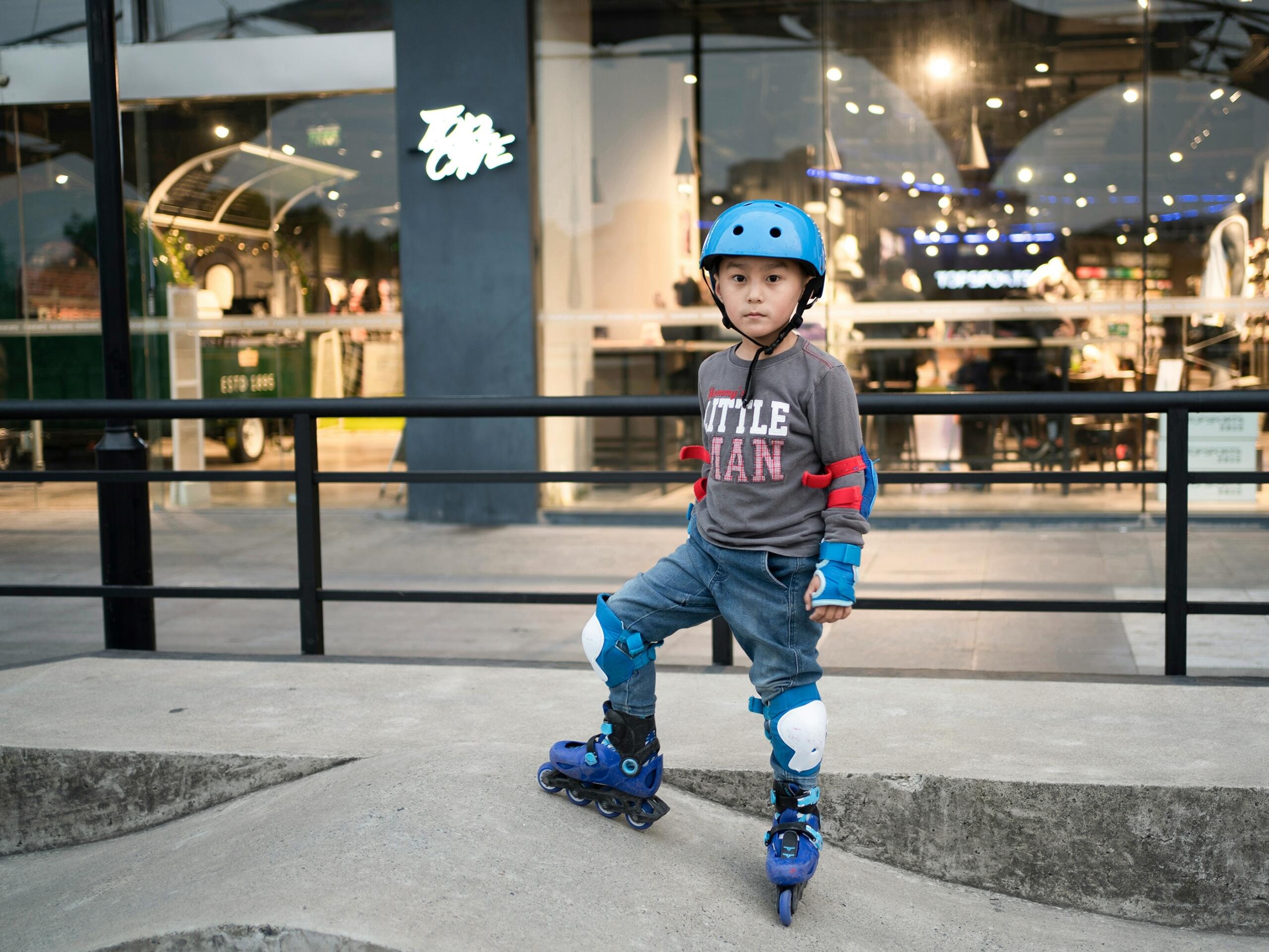 A boy with a helmet getting reading to roller skate.