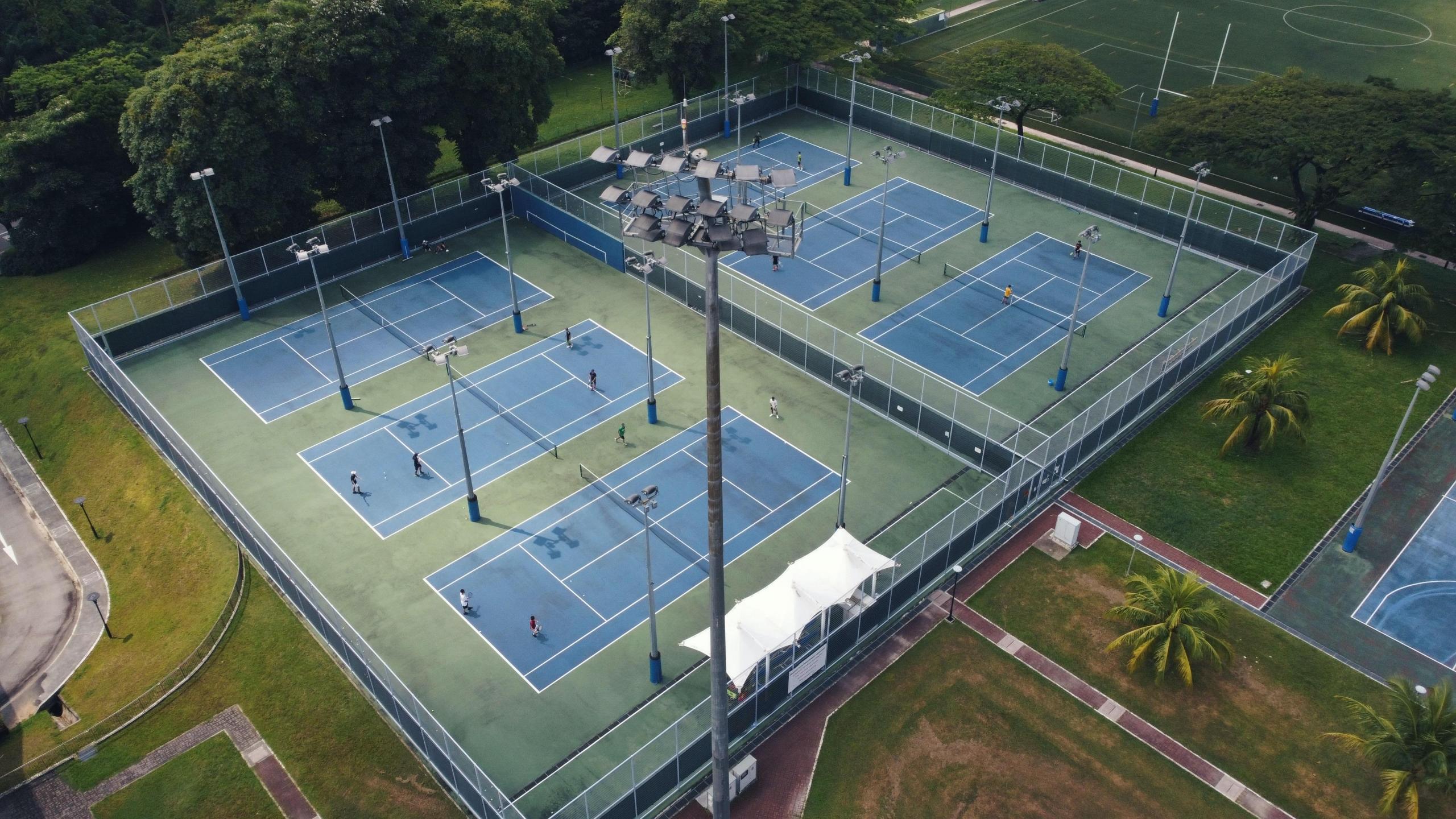 Multiple tennis players are practicing on courts