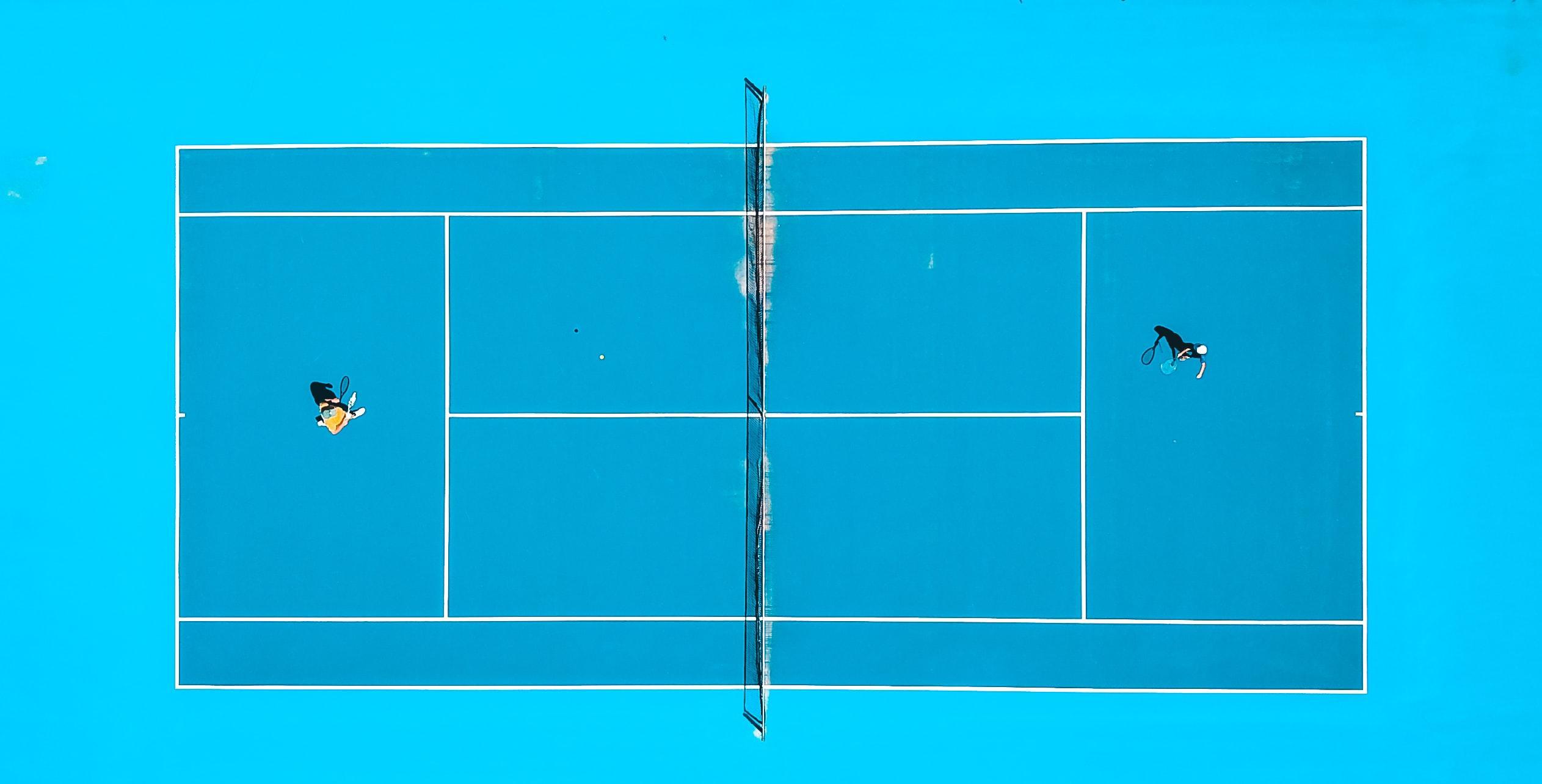 An aerial shot of two people playing on a tennis court
