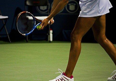 A tennis player getting ready to serve the ball with their racket