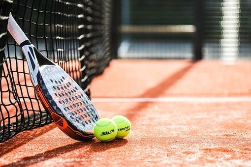 A tennis racket and balls resting in a court