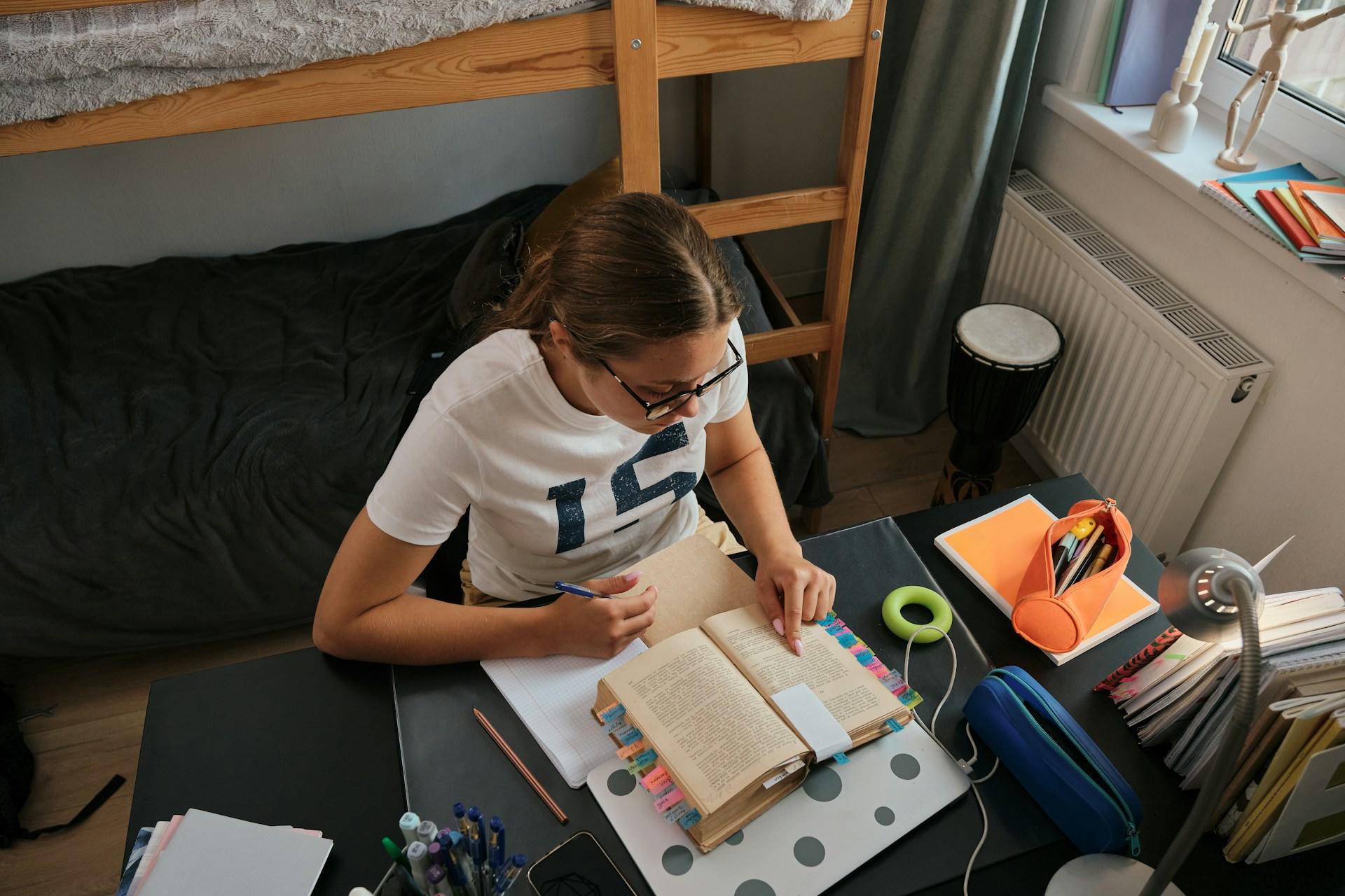 A girl doing homework at her desk in her dorm.