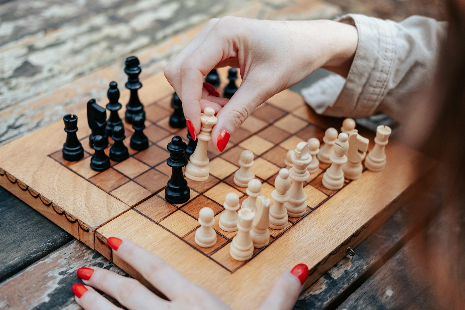 A girl playing chess on a wooden board.