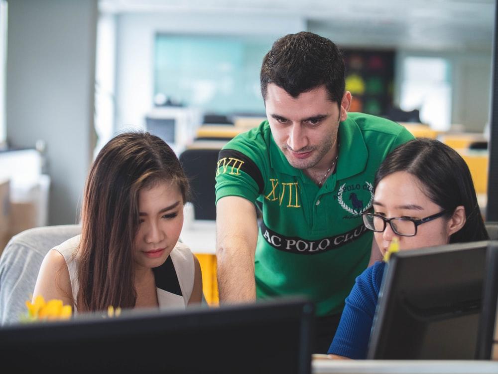 A facilitator helping two students with a computer program