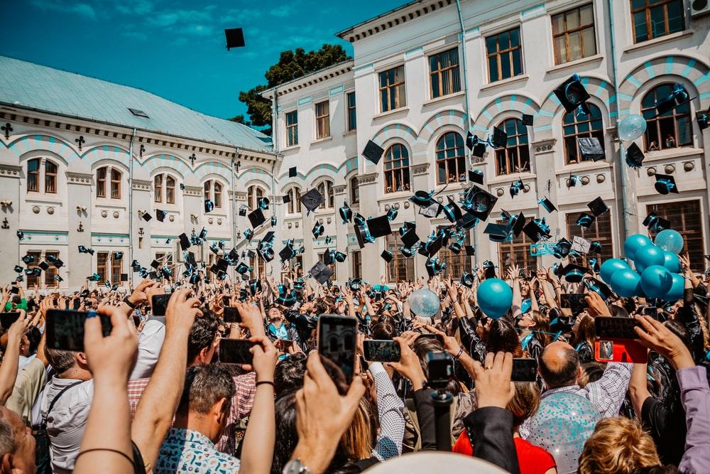 A crowd of students throwing their hats in celebration of their graduating on the front lawn of the University during a convocation ceremony