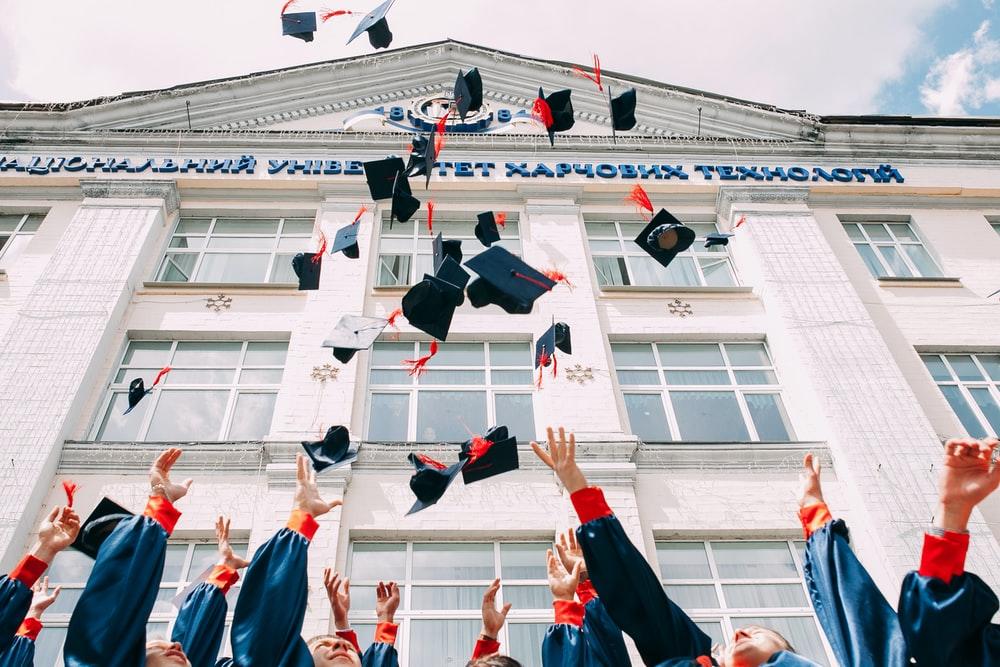 College graduates tossing their hats in the air in front of university after the convocation ceremony