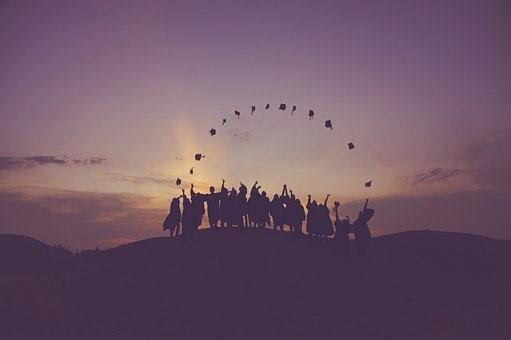 A silhouette of students throwing their hats in their air