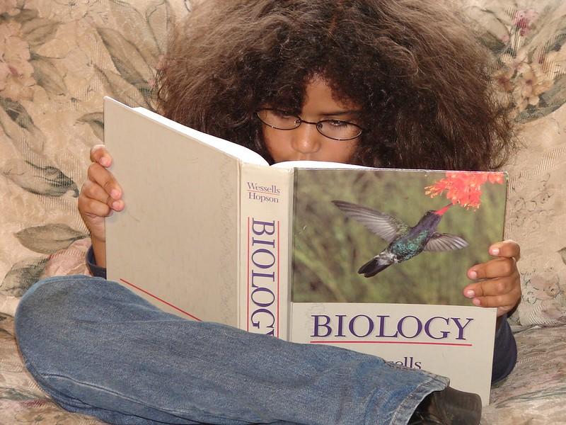 A girl reading a book titled 'Biology.'