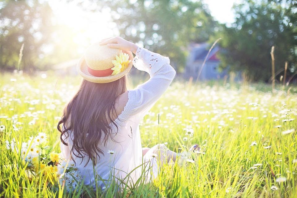 A woman sitting on a field under the summer sun