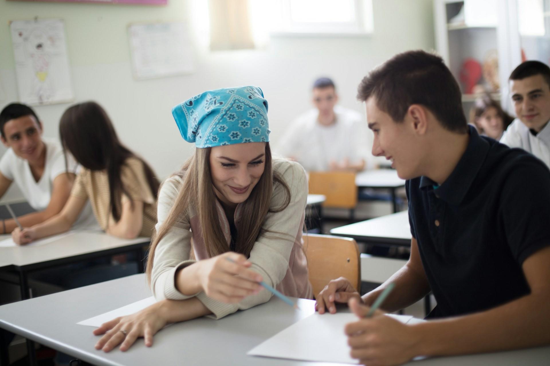 A girl in a bandana talking to a boy.