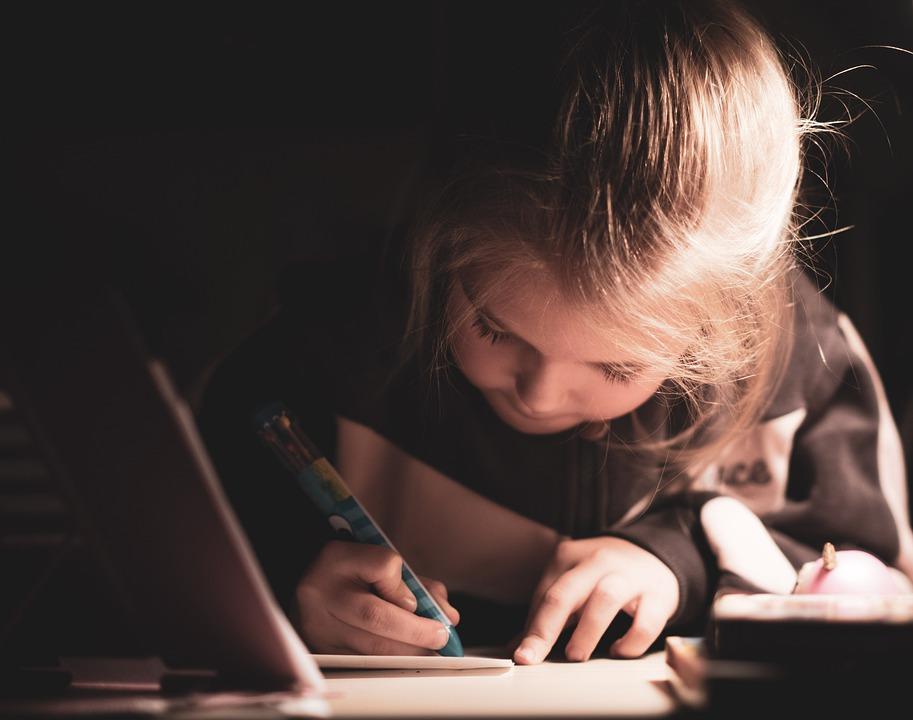 A little girl writing with a pen