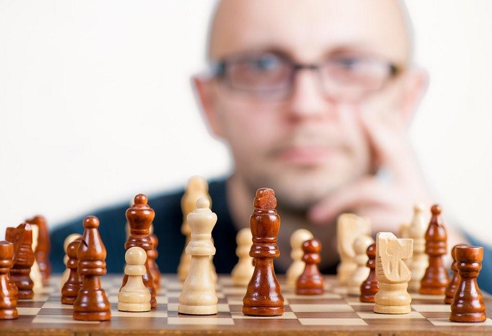 A guy in glasses observing a chess set