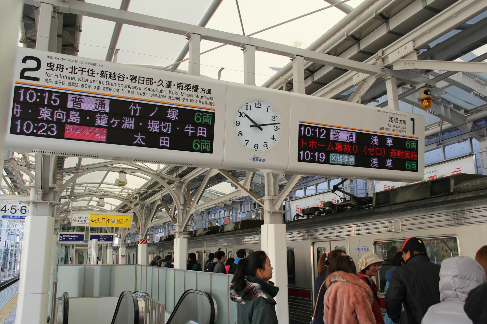 a notice board in a Japanese train station showing words written in Japanese and numbers written in Arabic numerals