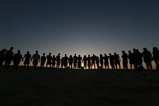 A silhouette of a large group of people standing in a line