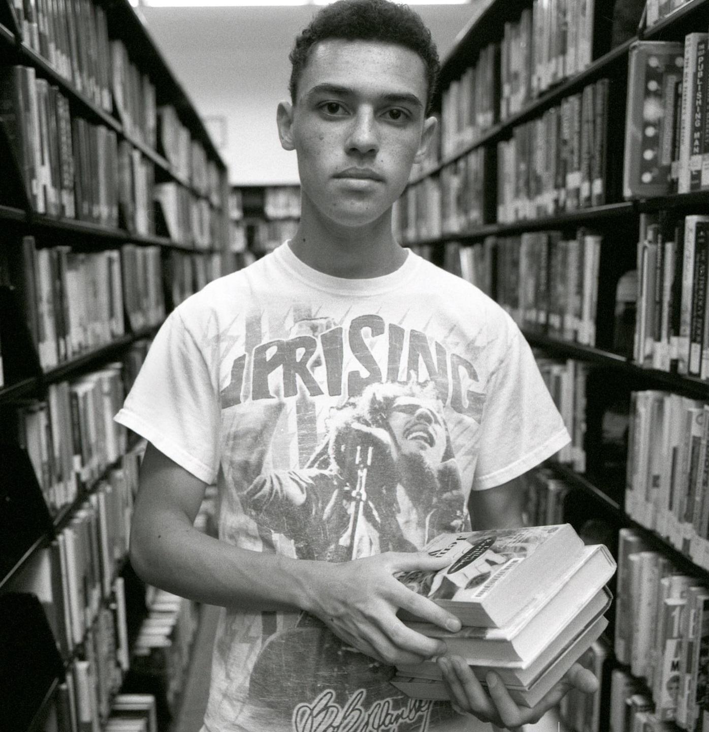 A high school student holding books in the library
