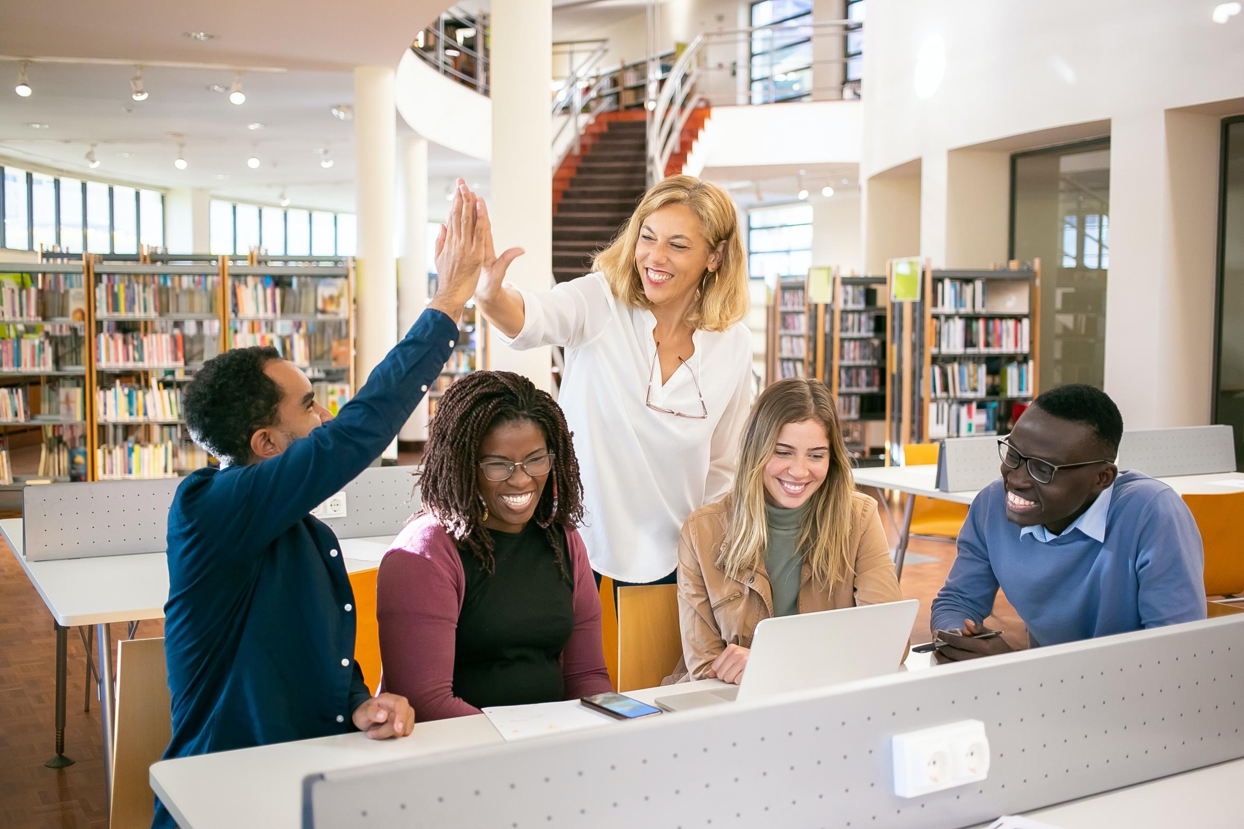 students and tutor studying in a library