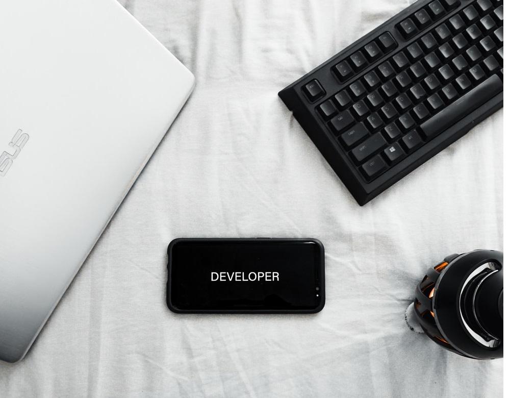 A smartphone lying on a white sheet with developer written on the screen