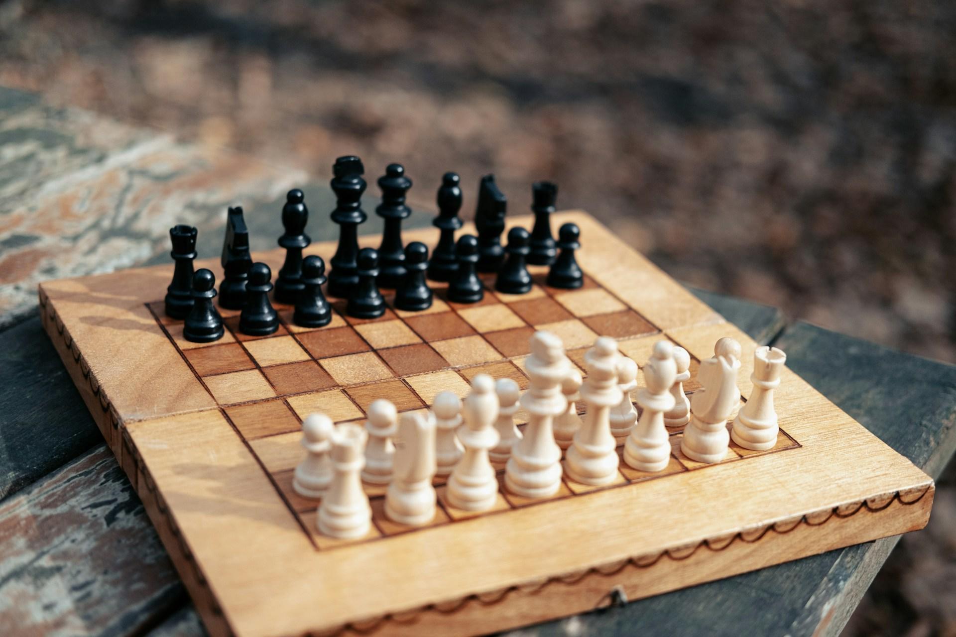 A wooden chess board with white and black pieces.