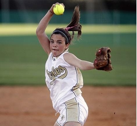 A girl is in full swing, pitching the baseball