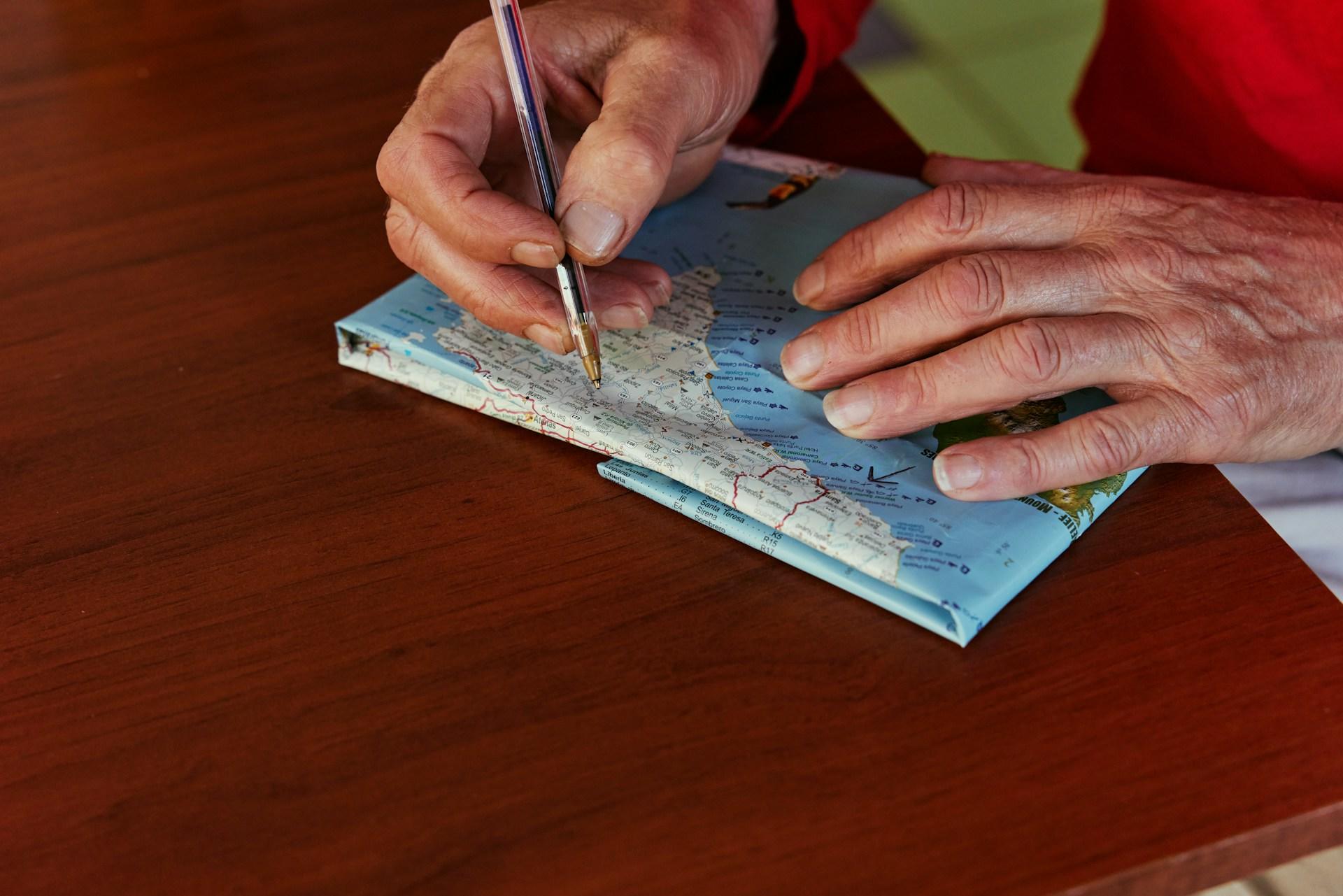 A man writing with a pen on a map.